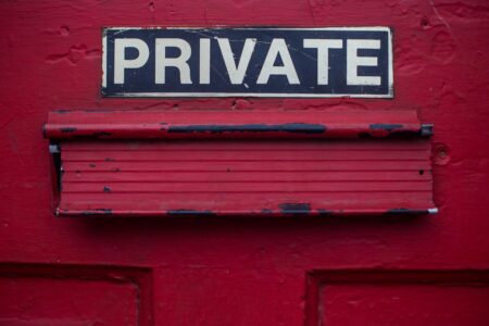 A mail slot in a red door under a sign that says Private