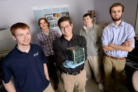 UND students, part of a collaboration with students from NDSU in Fargo, show of their version of a “CubeSat,” a miniature satellite that is slated to be launched into space and orbit the Earth early next year. In the image, left to right, are Skye Leake, Michael Hirsch, Christian Peterson, Jeremy Straub and Karl Schmaltz.  Straub is heading up the project at UND and NDSU. He is a Ph.D. graduate of UND’s Computer Sciences Department and currently works as a faculty member in NDSU’s Computer Science division. Photo by Jackie Lorentz.