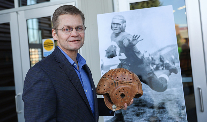 Glenn James Jarrett, grandson of UND Athletics legend Glenn "Red" Jarrett, holds one of his grandfather's leather football helmets, during a dedication ceremony that put the elder Jarrett's name on the entrance of the school's High Performance Center. Photo by Jackie Lorentz/UND Today. 

Officials from the University of North Dakota Athletic Department and Alumni 
Association and Foundation held a a special ceremony Oct. 20, 2017 to honor Glenn "Red" Jarrett at the High Performance Center in the dedication of "Glenn Red Jarrett Way". 

Glenn James Jarrett holds one of his grandfathers Glenn Red Jarrett's leather football helmets in front of a photo of his grandfather in a UND Football uniform. (Note not wearing the same helmet).