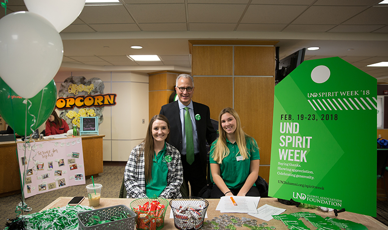 UND President Mark Kennedy dropped by the Spirit Week “Pay It Forward” table on Wednesday afternoon. One of the table attendants, UND Student Ambassador Allie Harvey (left), was notified just a couple of hours later that she had been randomly chosen for a $5,000 Spirit Week/Giving Hearts Day scholarship. Photo courtesy of Sam Melquist/UND Alumni Association & Foundation.