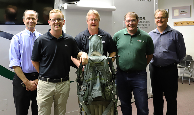(Left to right) )Robert Kunze, Brennan Granger, Steve Martin, Sanford Fogg and Tom Zeidlik stand behind the ACES II ejection seat donated by retired Air Force Lt. Col. Stephen Granger with the help of his son, Brennan. Granger was allowed to keep the seat after it saved his life in 2005, which he eventually passed to Brennan when he came to UND. Photo by Connor Murphy/UND Today.