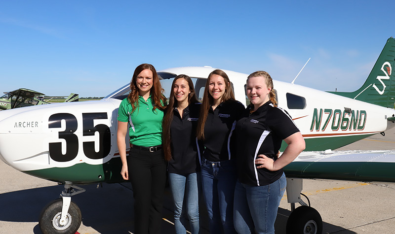 From left to right: UND Assistant Chief Flight Instructor and coach Erin Roesler, Monique McAnnally, Dakotah Osborn, and Jenna Annable stand in front of ‘Evelyn’, the Piper Archer aircraft they will use in 2018’s Air Race Classic. Missing from the group photo is Emily Hartley, the team’s ground coordinator, as she was completing her certification as a UND flight instructor. Photo by Connor Murphy/UND Today.