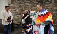 Fort Berthold Reservation physician and councilwoman for the Three Affiliated Tribes Dr. Monica Mayer embraces UND First Lady Kathy Armacost, after presenting the First Lady and President Armacost with traditional star quilts as gifts during a visit by UND leaders to the Tribe's new Interpretive Center in New Town, N.D. on July 29, 2021. Three Affiliated Tribes Chairman Mark Fox (at left) looks on with Dr. Don Warne, director of UND's Indians into Medicine program, in the foreground. Both Fox and Dr. Mayer are UND alumni. Photo by David Dodds.