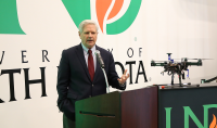U.S. Sen. John Hoeven, R-N.D., speaks at a press conference at UND announcing $5 million in new funding for a project to develop an augmented-reality system for Army Humvees. To the right, a UND drone and a Humvee are on display. Photo by David Dodds/UND Today.