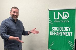 Professor Kilzer stands next to UND Sociology banner.