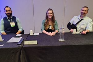 Three people sit at table.