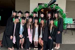 graduating students stand in group wearing regalia