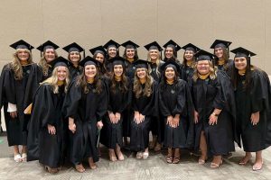 students stand in group wearing academic regalia