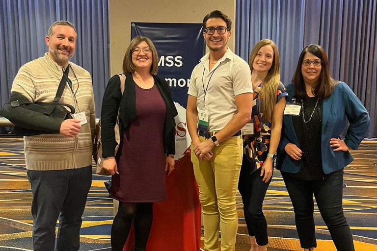 five people standing and smiling