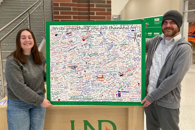 two people hold poster board covered with hand written notes