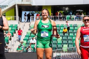 CSD student-athlete Kenna Curry holds NCAA Track & Field trophy in uniform