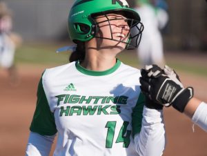 CSD student-athlete Isabella Haslett in softball uniform, smiling in helmet with field out of focus in the background