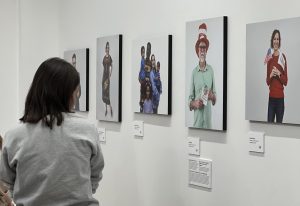 Back of person reading about portraits hanging on a white wall.