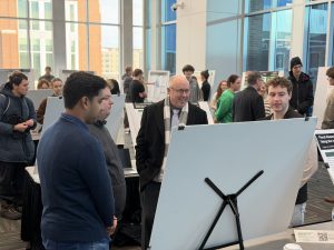Dean Brad Rundquist smiling at posterboard presentation with students