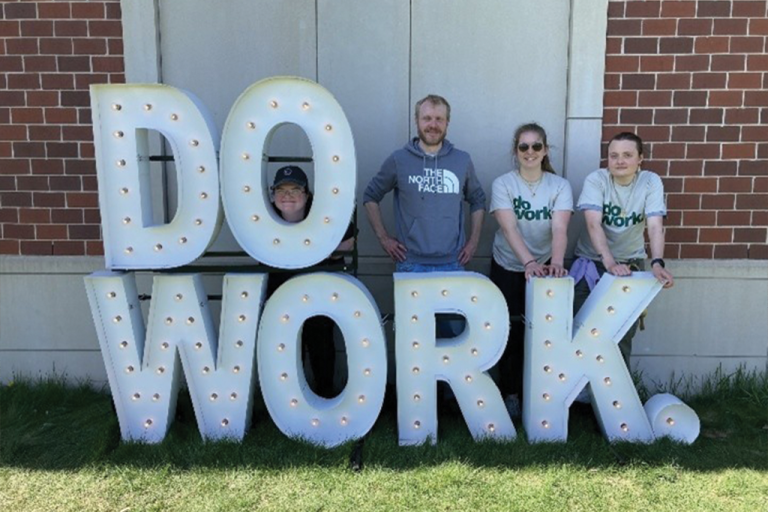Sociology students pose wtih white lit letters of "Do Work." during the Big Event, an annual volunteer day.