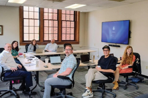Seven members of the sociology faculty collected around working tables in a classroom.