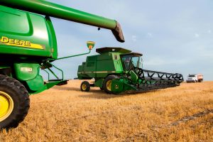 View from combine John Deere harvester, John Deere combine in background with grain truck background approaches combines