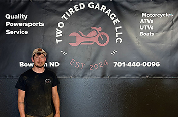owner, Bondon standing in front of a wall in their shop in front of their logo