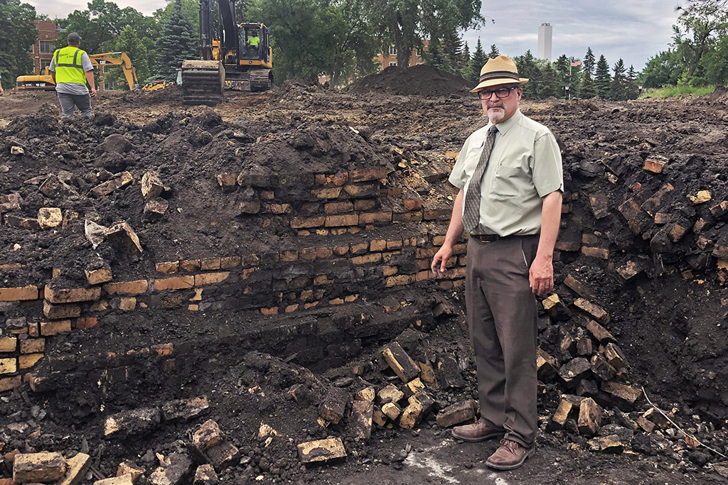 Darin Buri stands in front of dug up remains of foundation