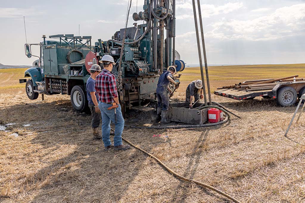 Group of people work surround drilling equipment outside