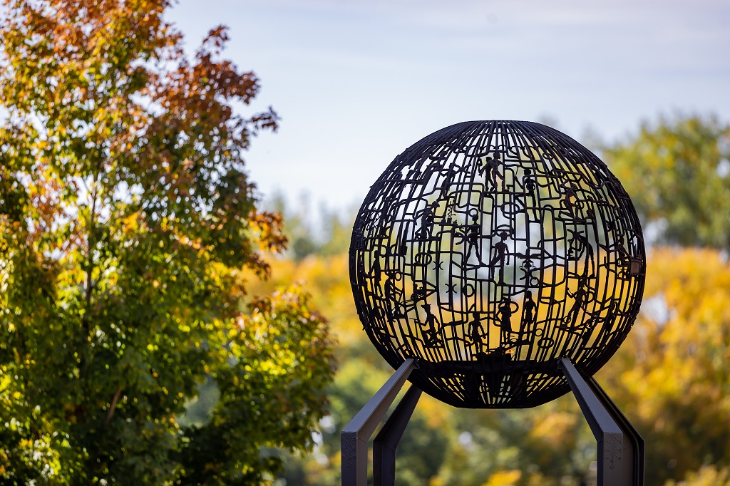 The iconic Eternal Flame sculpture pictured on a beautiful fall day with tree leaves turning yellow in the background.