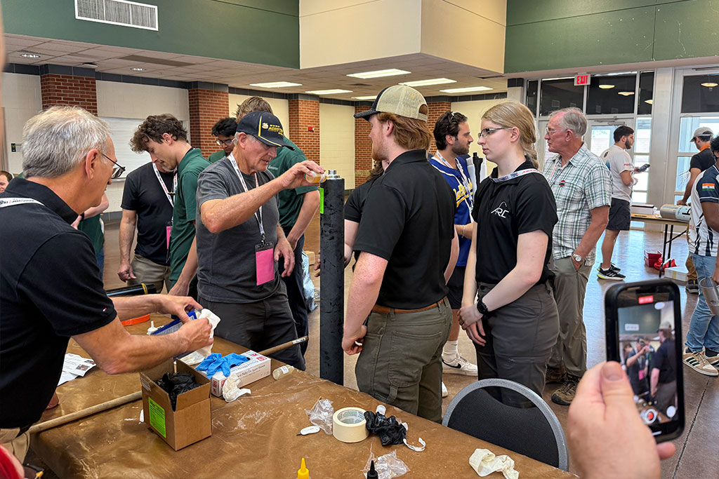 Students talk with event staff and visitors with their rocket nearby.