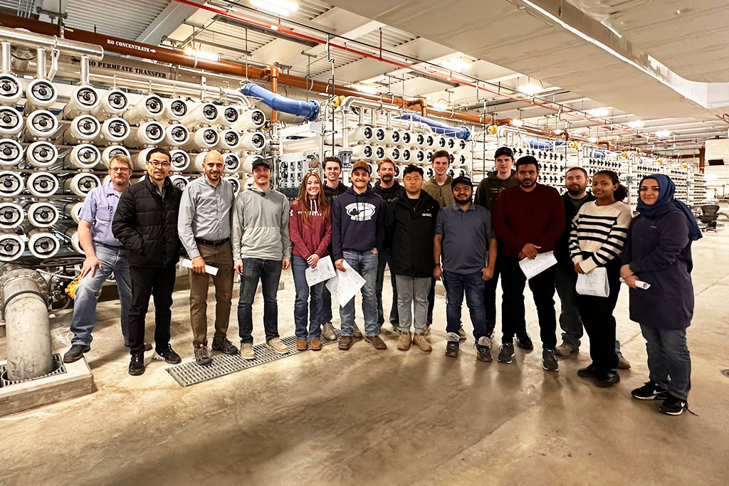 Fifteen people stand for a group photo and smile inside of the City of Fargo Water Treatment Plant.