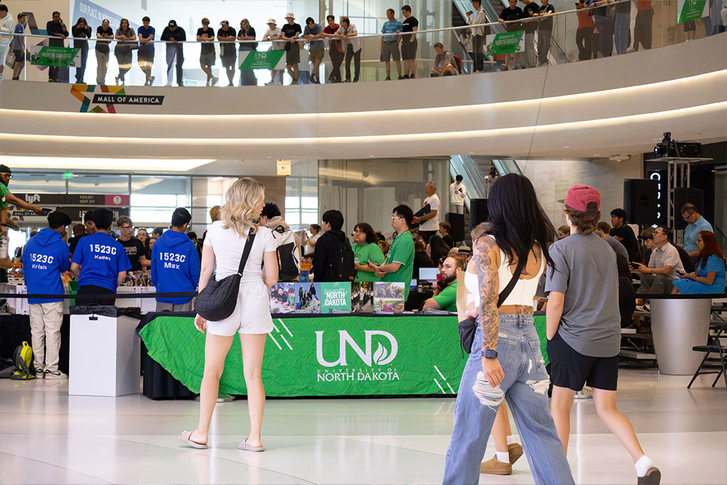 Mall visitors walk past a UND recruitment booth and an event packed with spectators.