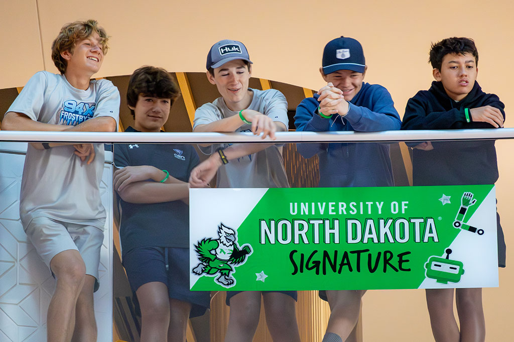 Five students watch a robotics competition from one of the atrium's many balconies.
