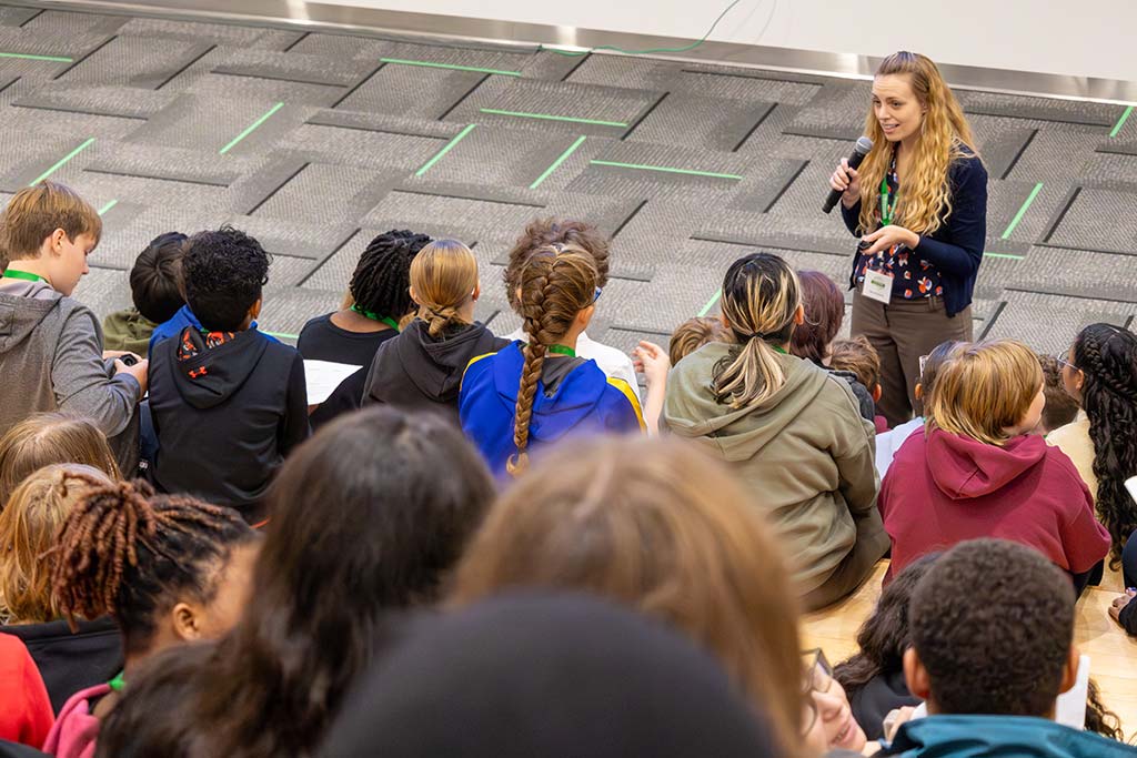 A woman speaks to a group of listening students at the University of North Dakota Memorial Union Social Staircase.
