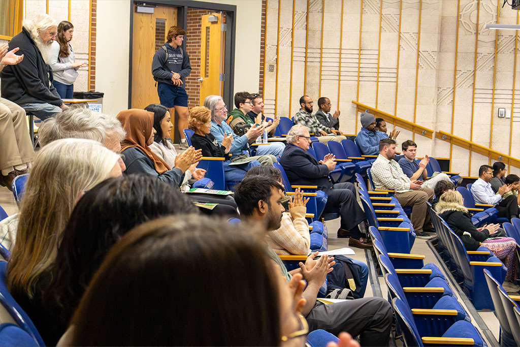 The Univeristy of North Dakota Leonard Hall Lecture Bowl is filled with student, alumni, faculty and staff as they clap their hands.