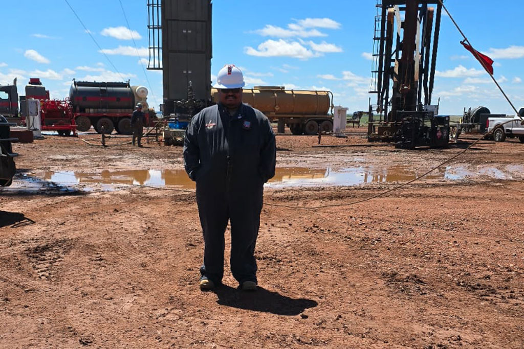 A person wearing a hard hat stands in an outdoor worksite for an oil rig in Dickinson, North Dakota.