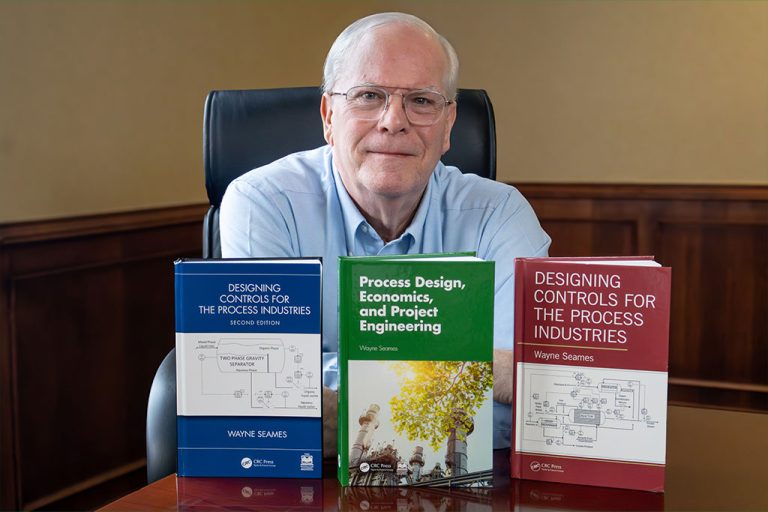 University of North Dakota Chemical Engineering professor Wayne Seames sits in a chair behind three of his displayed textbooks.