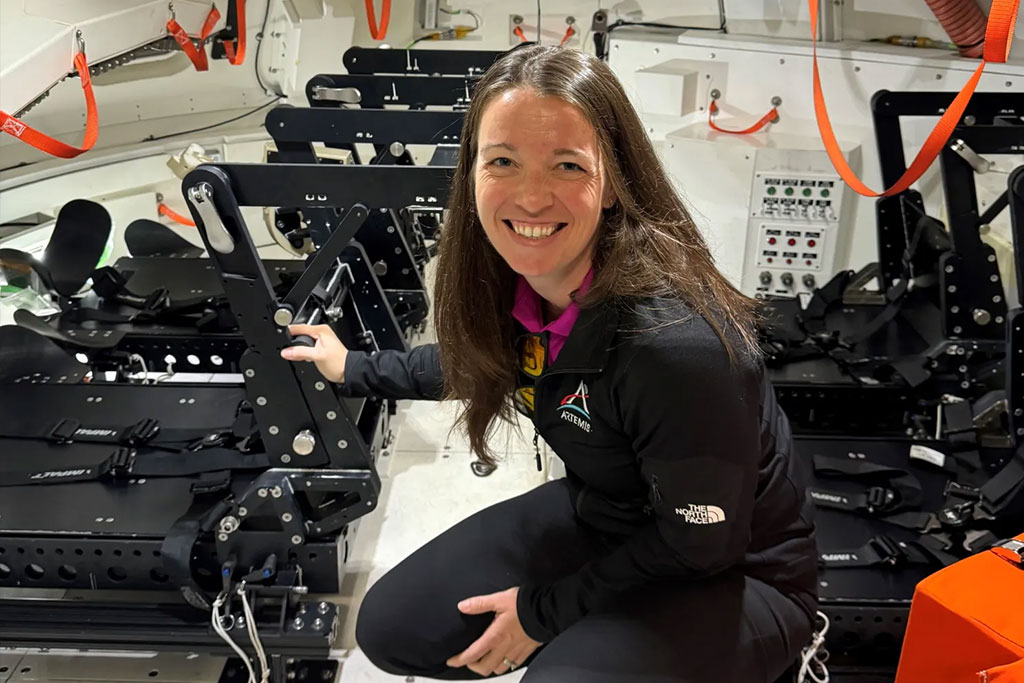 A person kneels inside a spacecraft's interior.