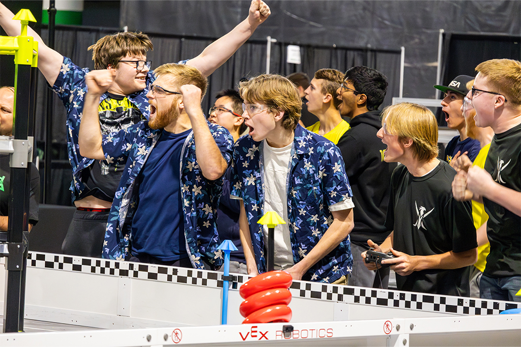 Students jump and cheer in excitement at a robotics competition.