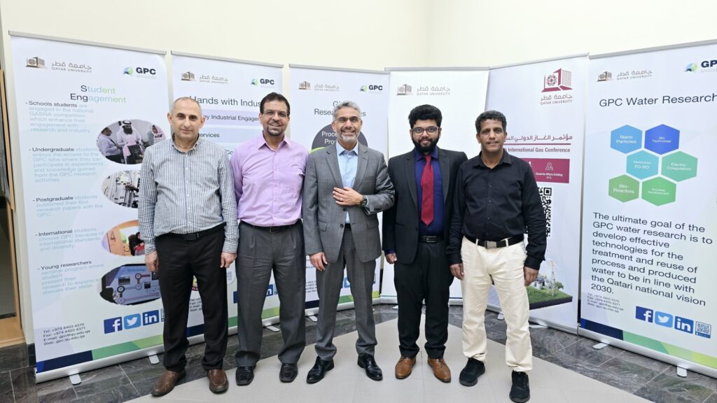 Five people stand in front of research posters for a group photo.