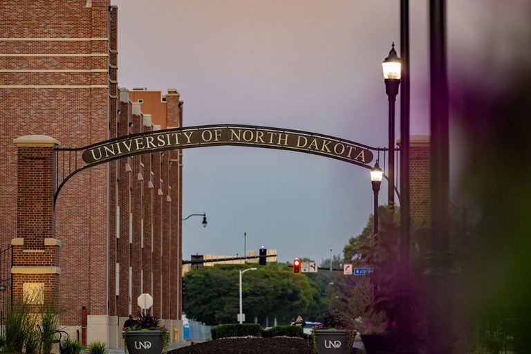 A cinematic view of the University of North Dakota campus with lit street lamps and a stoplight intersection in the distance.