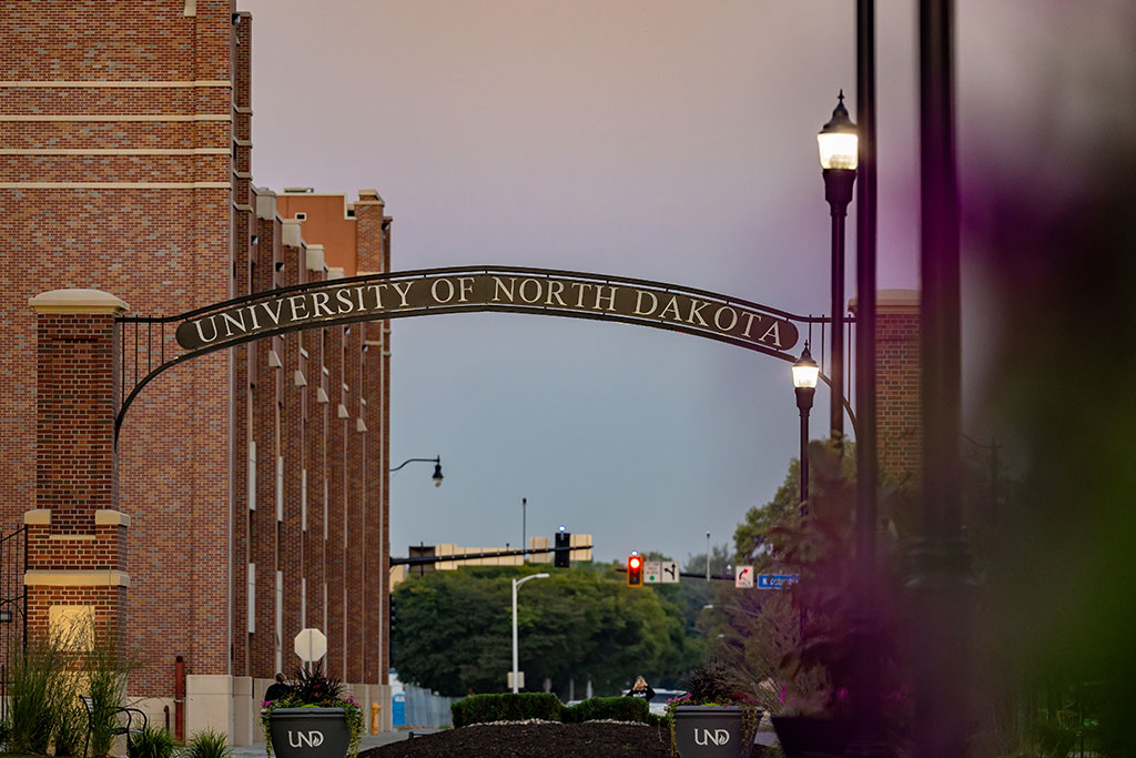 A cinematic view of the University of North Dakota campus with lit street lamps and a stoplight intersection in the distance.