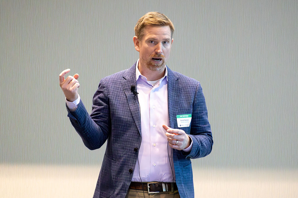 A person in a suit speaks while holding a microphone.