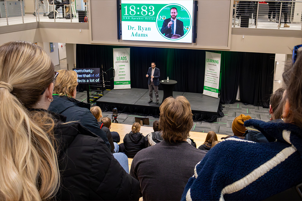 Dean Ryan Adams of the University of North Dakota College of Engineering & Mines speaks on a small stage in front of many people at the Memorial Union Social Staircase.