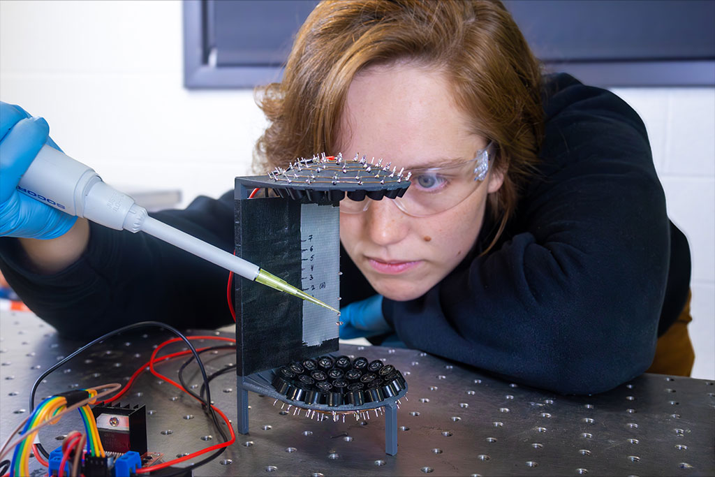A student uses a pipette to suspend droplets of water in the air using a piece of laboratory equipment that allows the particles to levitate.