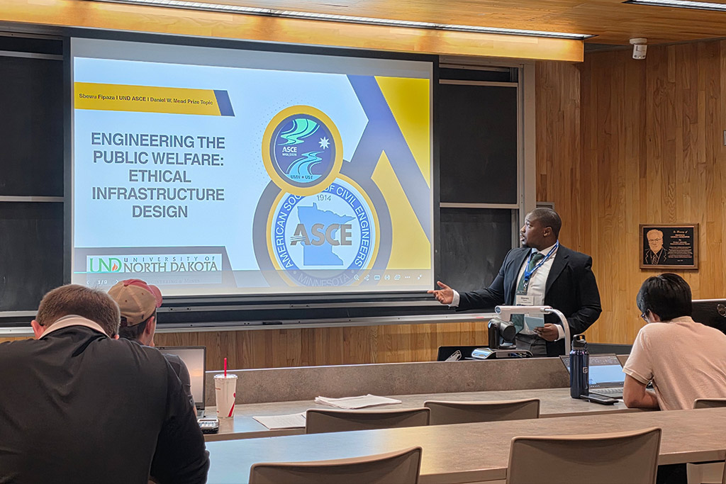 A student stands at a podium as he presents a presentation titled "Engineering the Public Welfare: Ethical Infrastructure Design."