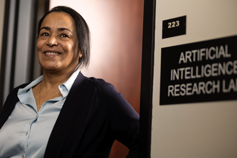 University of North Dakota faculty member Dr. Naima Kaabouch smiles at the doorway of the Artificial Intelligence Research Lab located in Harrington Hall.