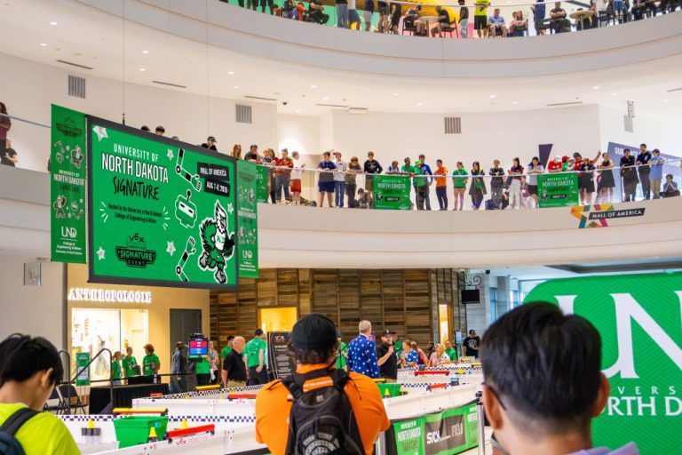 Hundreds of spectators stand around the Mall of America North Atrium's glass railings to overlook a robotics tournament hosted by the University of North Dakota.
