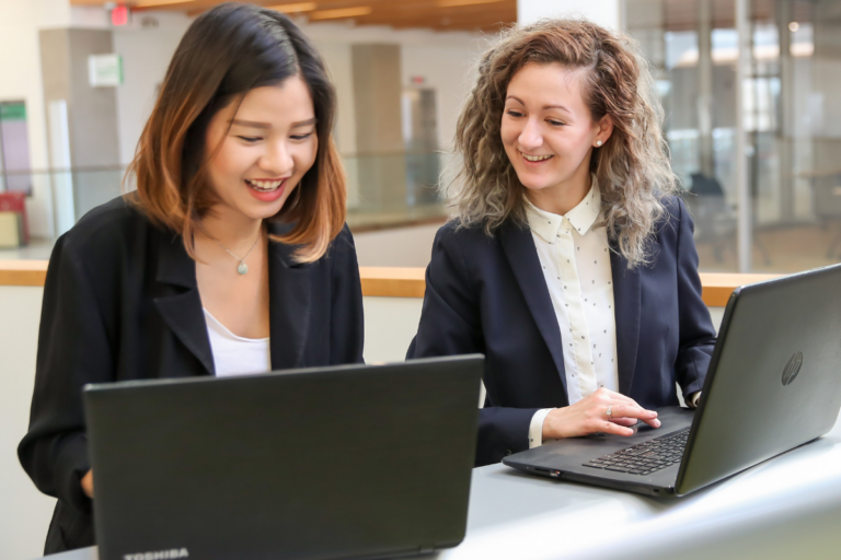 two students looking at laptops together