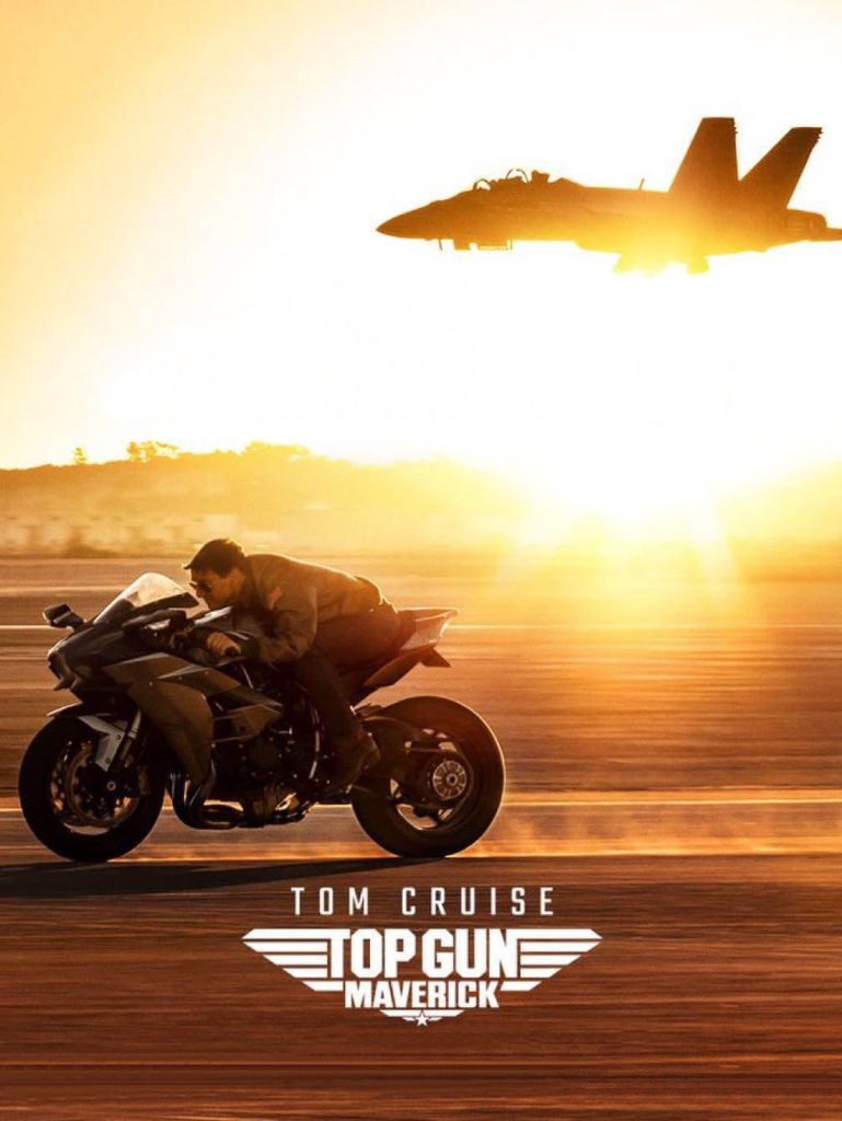 Movie poster for Top Gun: Maverick, depicting the hero riding his motorcycle at a high speed, with a fighter jet and sunset in the background.