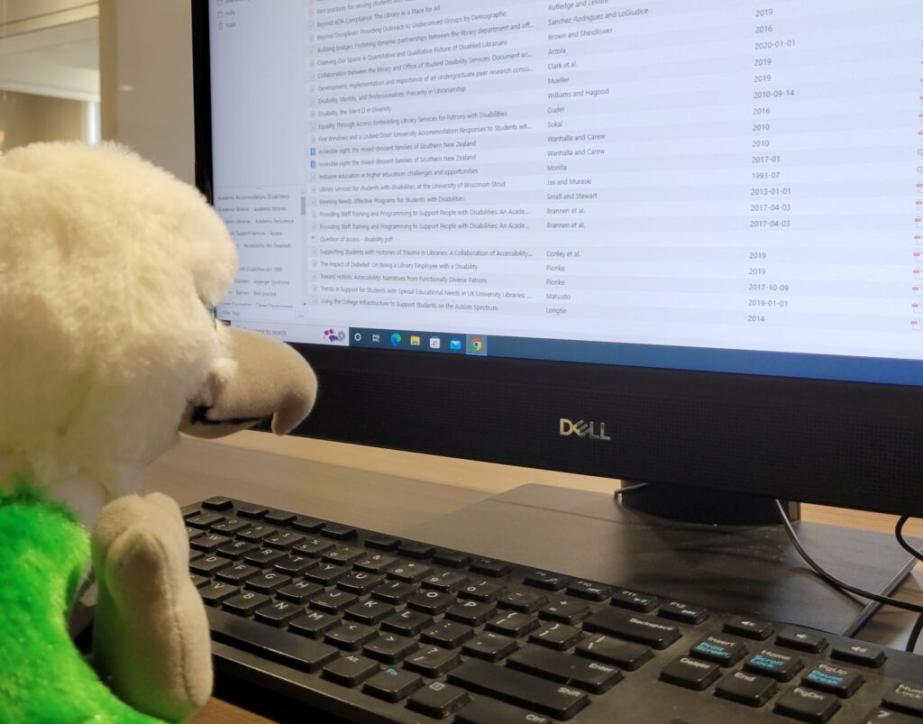 a plush bird in front of a computer screen showing the Zotero library