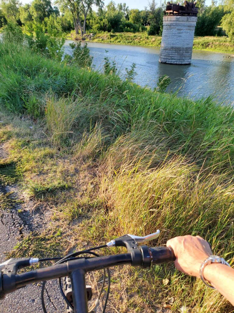 a bike on a grassy path alongside a calm river