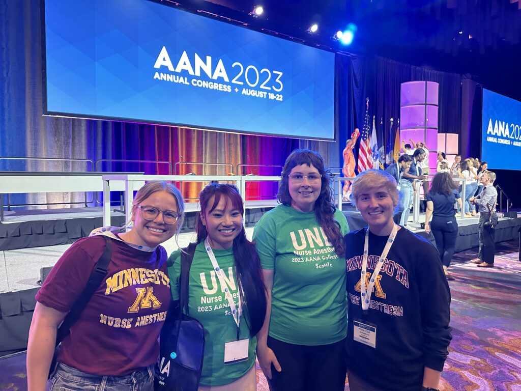 four students in front of a stage