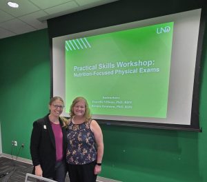 Dr. Swanson and Dr. Villano stand infront of their presentation on Practice Kills Workshop on Nutrition-Focused Physical Exams.